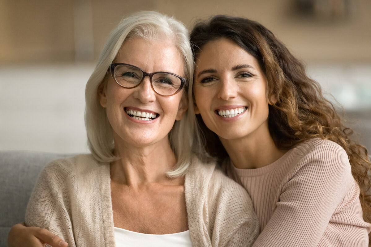 Happy elderly mom and young daughter woman posing at home